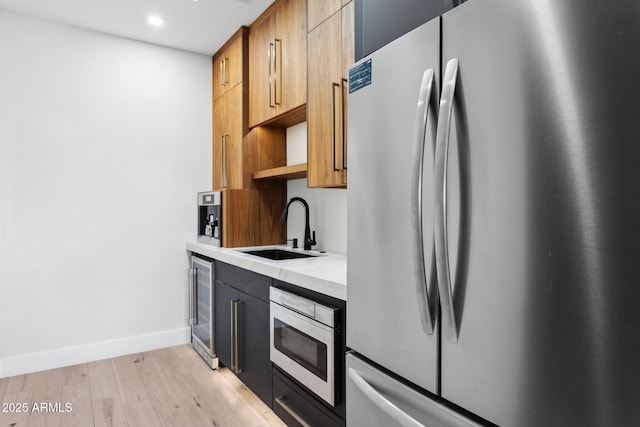 kitchen featuring open shelves, appliances with stainless steel finishes, a sink, light wood-style floors, and light countertops