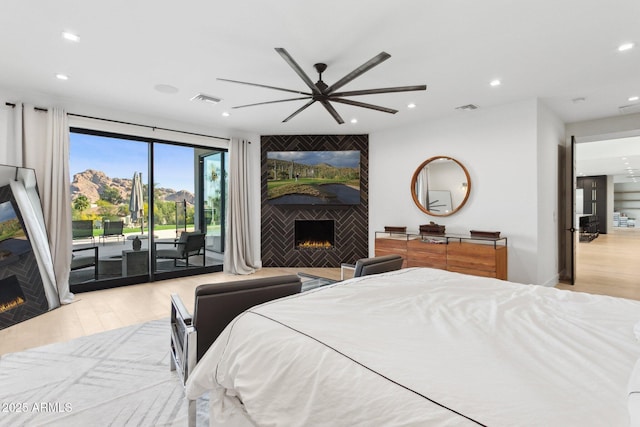 bedroom with access to outside, a fireplace, wood finished floors, and visible vents