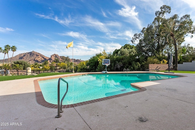 outdoor pool with fence, a mountain view, and a patio area