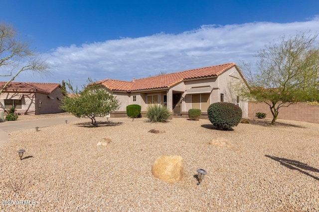 mediterranean / spanish home featuring a tile roof, fence, and stucco siding