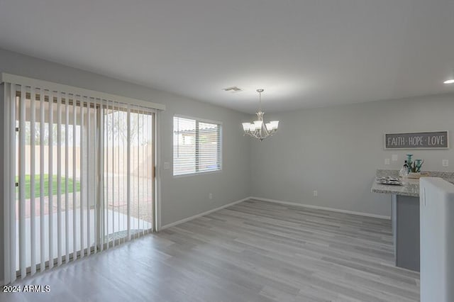 unfurnished dining area featuring light hardwood / wood-style flooring and a notable chandelier