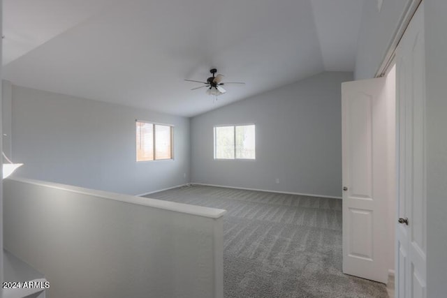 carpeted spare room with ceiling fan and vaulted ceiling