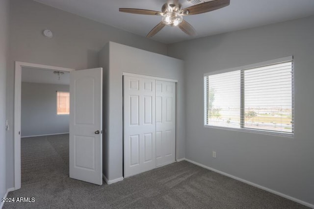 unfurnished bedroom with dark carpet, a closet, and ceiling fan