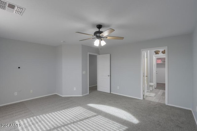 unfurnished bedroom featuring ceiling fan, ensuite bathroom, and light carpet