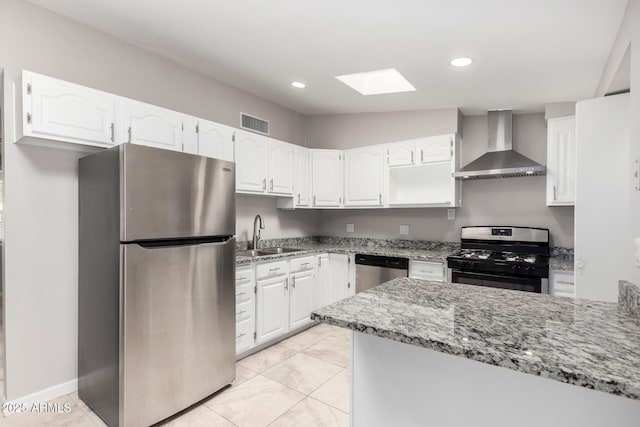 kitchen featuring visible vents, wall chimney exhaust hood, appliances with stainless steel finishes, light stone countertops, and a sink