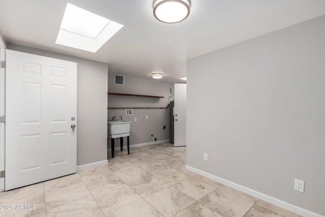 interior space featuring laundry area, baseboards, a skylight, and marble finish floor