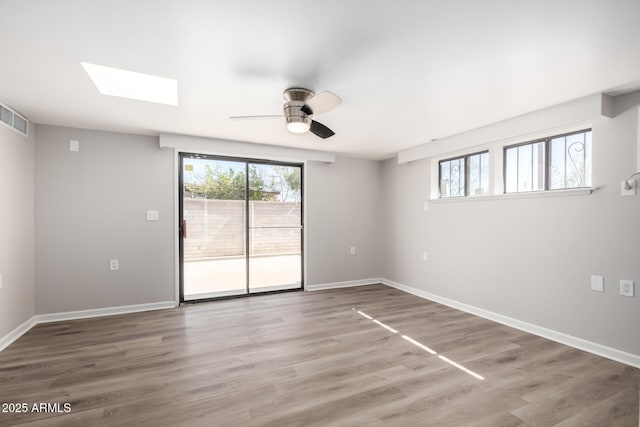 unfurnished room with wood finished floors, a ceiling fan, and baseboards