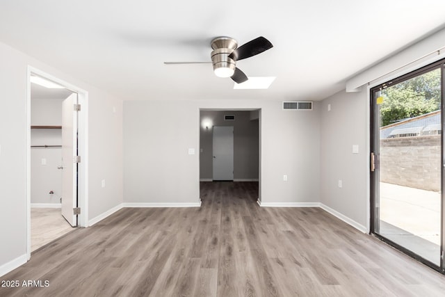 empty room featuring light wood-style floors, baseboards, and visible vents