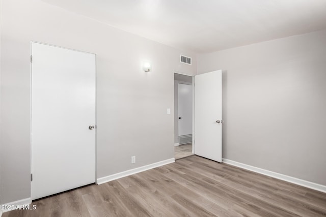 unfurnished room featuring light wood-style floors, baseboards, and visible vents