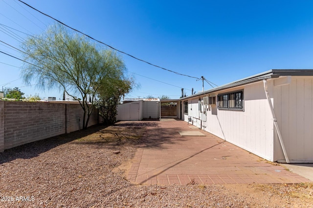 view of yard featuring a storage shed, a fenced backyard, a patio, and an outbuilding