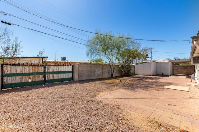 view of yard with an outbuilding, fence private yard, a gate, a storage unit, and a patio area