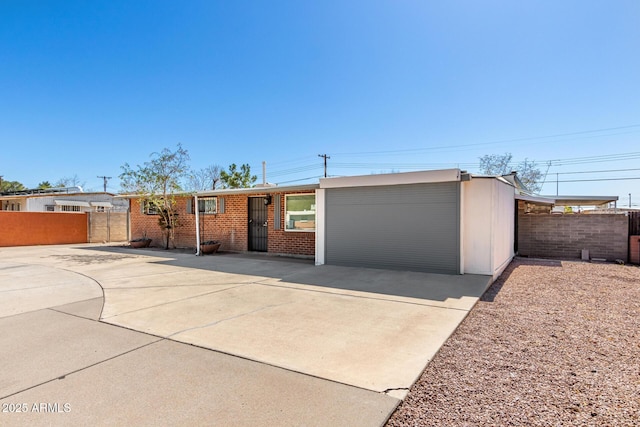 ranch-style home with driveway, fence, and brick siding