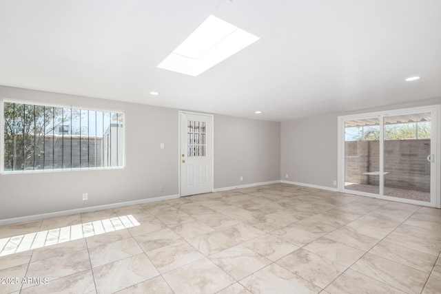 empty room with a skylight, baseboards, and recessed lighting