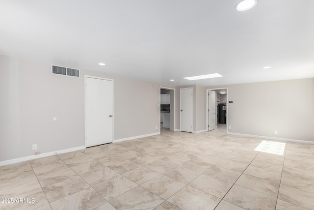 spare room with a skylight, baseboards, visible vents, and recessed lighting