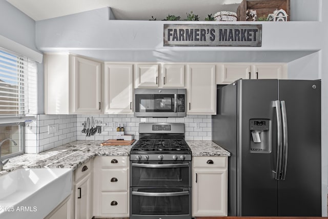 kitchen with tasteful backsplash, white cabinetry, appliances with stainless steel finishes, and sink