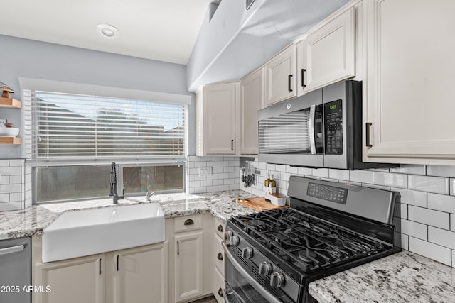 kitchen featuring white cabinetry, sink, light stone countertops, and appliances with stainless steel finishes