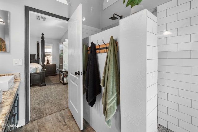 bathroom with vanity, wood-type flooring, and tiled shower