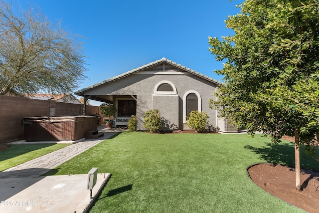 view of front of house featuring a front yard, a hot tub, and a patio area