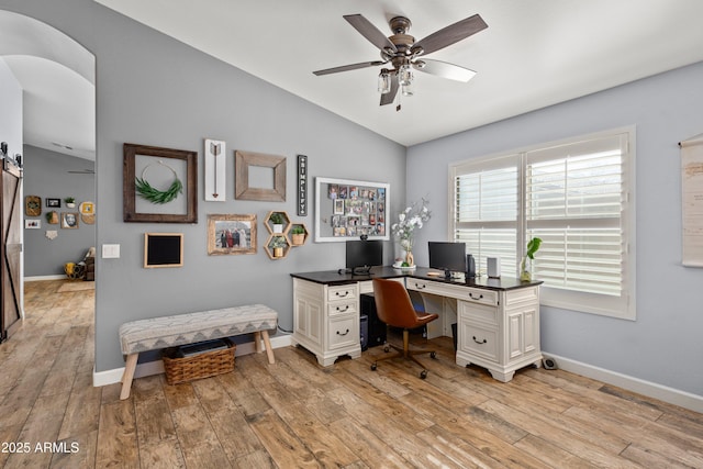 office with ceiling fan, lofted ceiling, a barn door, and light hardwood / wood-style flooring