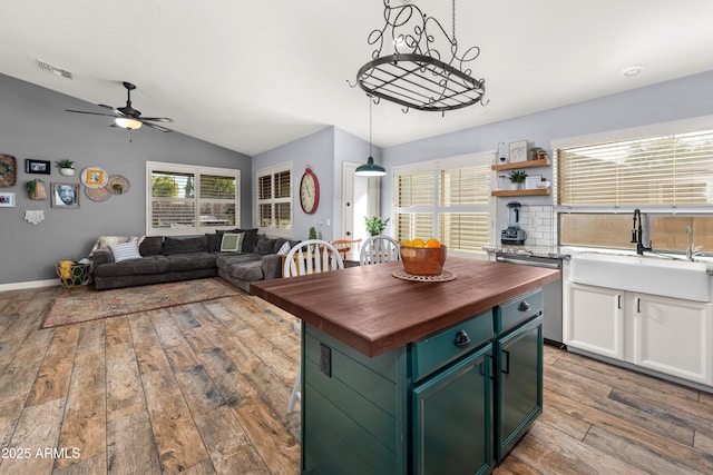 kitchen featuring light hardwood / wood-style flooring, wooden counters, white cabinetry, hanging light fixtures, and stainless steel dishwasher