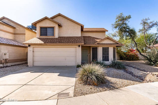 traditional home with roof with shingles, a garage, driveway, and stucco siding