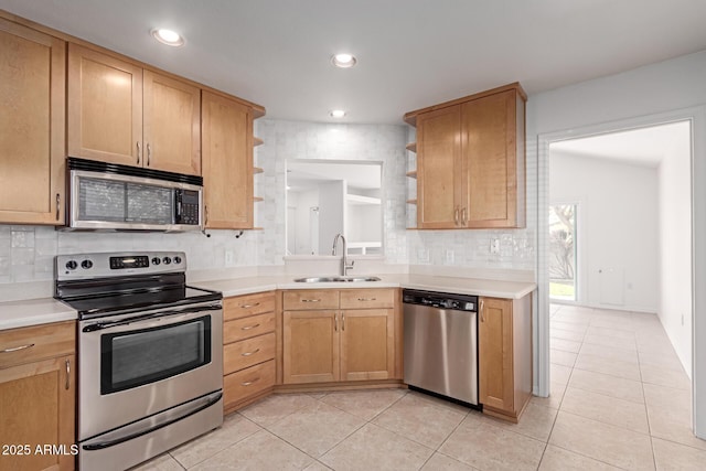 kitchen featuring open shelves, appliances with stainless steel finishes, light countertops, and a sink