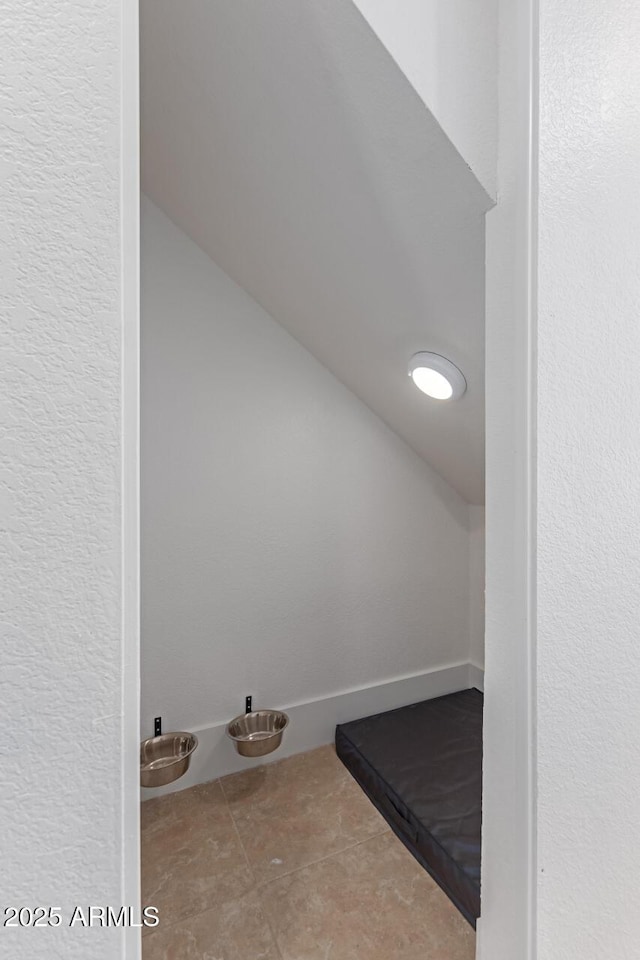 additional living space featuring tile patterned floors, baseboards, and lofted ceiling