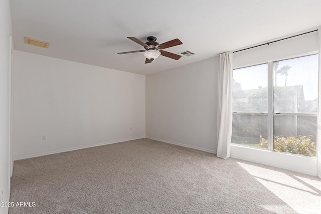 carpeted spare room with visible vents, baseboards, and ceiling fan