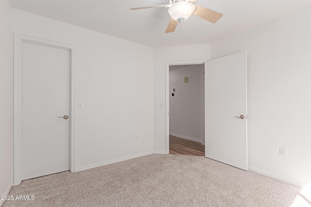 carpeted spare room featuring baseboards and a ceiling fan