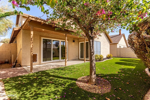 rear view of property featuring stucco siding, a patio area, a yard, and fence