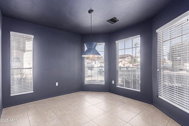 spare room featuring tile patterned flooring, visible vents, and a textured ceiling