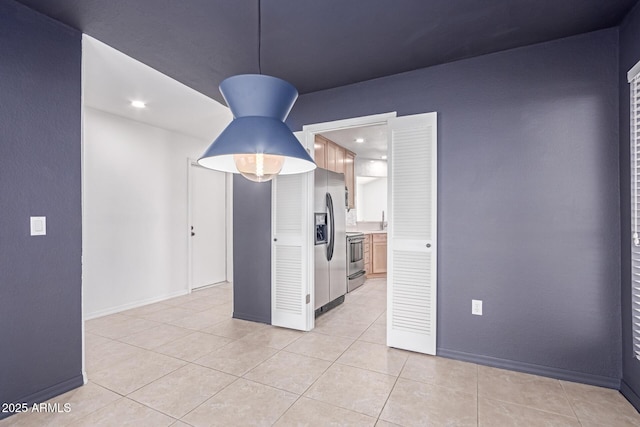 empty room featuring light tile patterned flooring, baseboards, and a sink