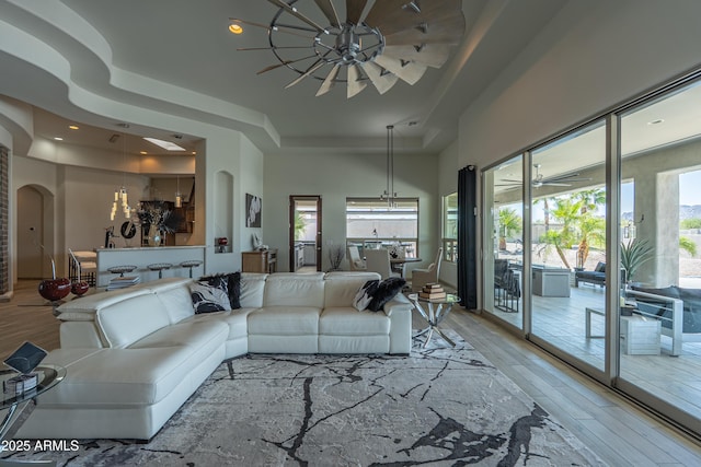 14332 E Bobwhite Way, Scottsdale, AZ 85262 - living room featuring a tray ceiling, a chandelier, light wood finished floors, arched walkways, and recessed lighting