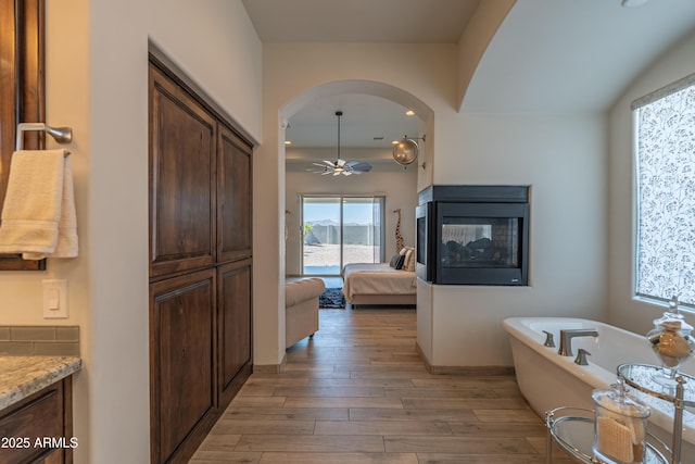14332 E Bobwhite Way, Scottsdale, AZ 85262 - ensuite bathroom featuring a freestanding tub, wood finished floors, vanity, a ceiling fan, and a multi sided fireplace