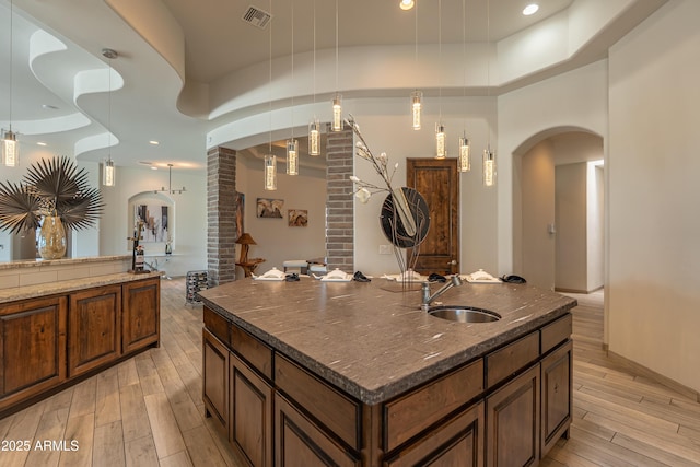 14332 E Bobwhite Way, Scottsdale, AZ 85262 - kitchen featuring arched walkways, light wood-type flooring, dark stone countertops, and recessed lighting