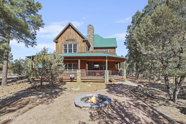 rear view of property with a porch and an outdoor fire pit