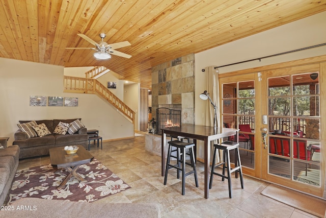 dining area featuring lofted ceiling, a tile fireplace, ceiling fan, light tile patterned flooring, and wooden ceiling