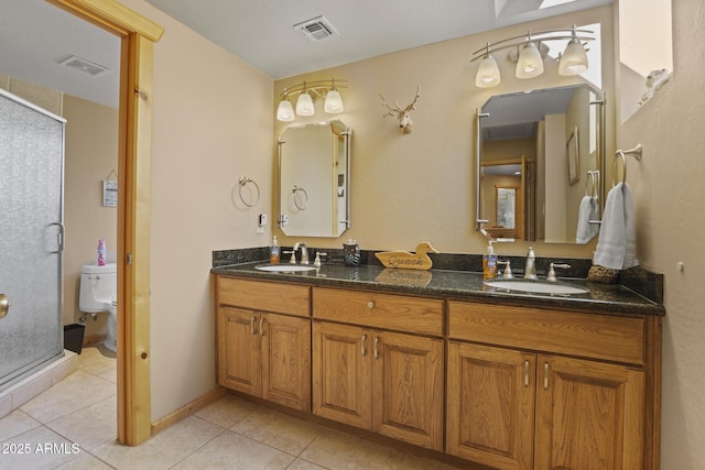 bathroom with tile patterned flooring, vanity, a shower with shower door, and toilet