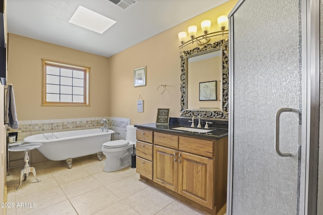 bathroom with a skylight, vanity, tile patterned floors, a tub, and toilet