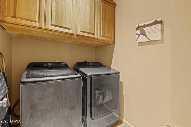 clothes washing area with cabinets and washing machine and clothes dryer