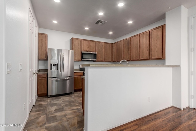 kitchen featuring brown cabinets, recessed lighting, visible vents, appliances with stainless steel finishes, and a peninsula