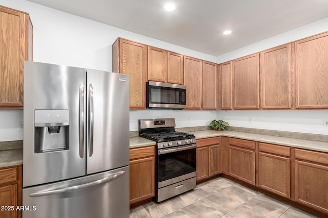 kitchen with brown cabinets, appliances with stainless steel finishes, light countertops, and recessed lighting