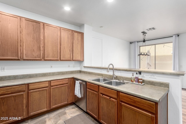 kitchen featuring visible vents, brown cabinets, a peninsula, stainless steel dishwasher, and a sink