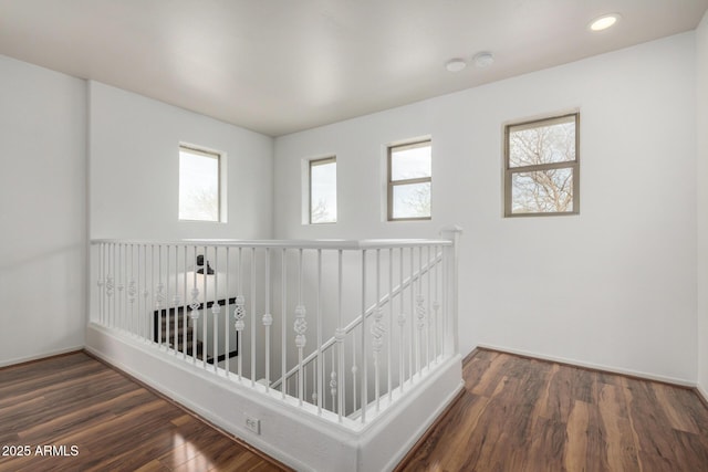 hall with an upstairs landing, baseboards, wood finished floors, and recessed lighting