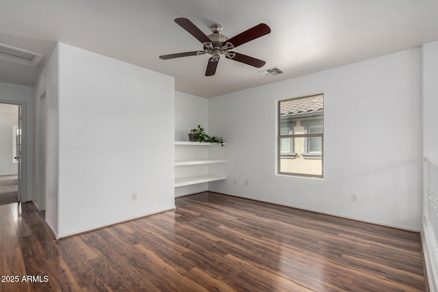 spare room featuring attic access, a ceiling fan, visible vents, and wood finished floors