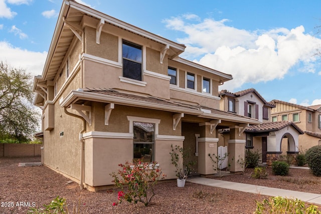 view of front facade with fence and stucco siding