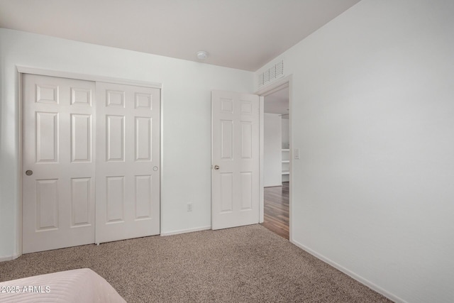 unfurnished bedroom with a closet, carpet flooring, visible vents, and baseboards