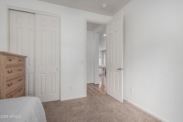 carpeted bedroom with a closet and baseboards