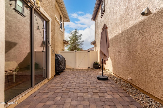 view of patio featuring grilling area, fence, and a gate