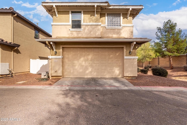 view of front of house featuring driveway, an attached garage, fence, and stucco siding